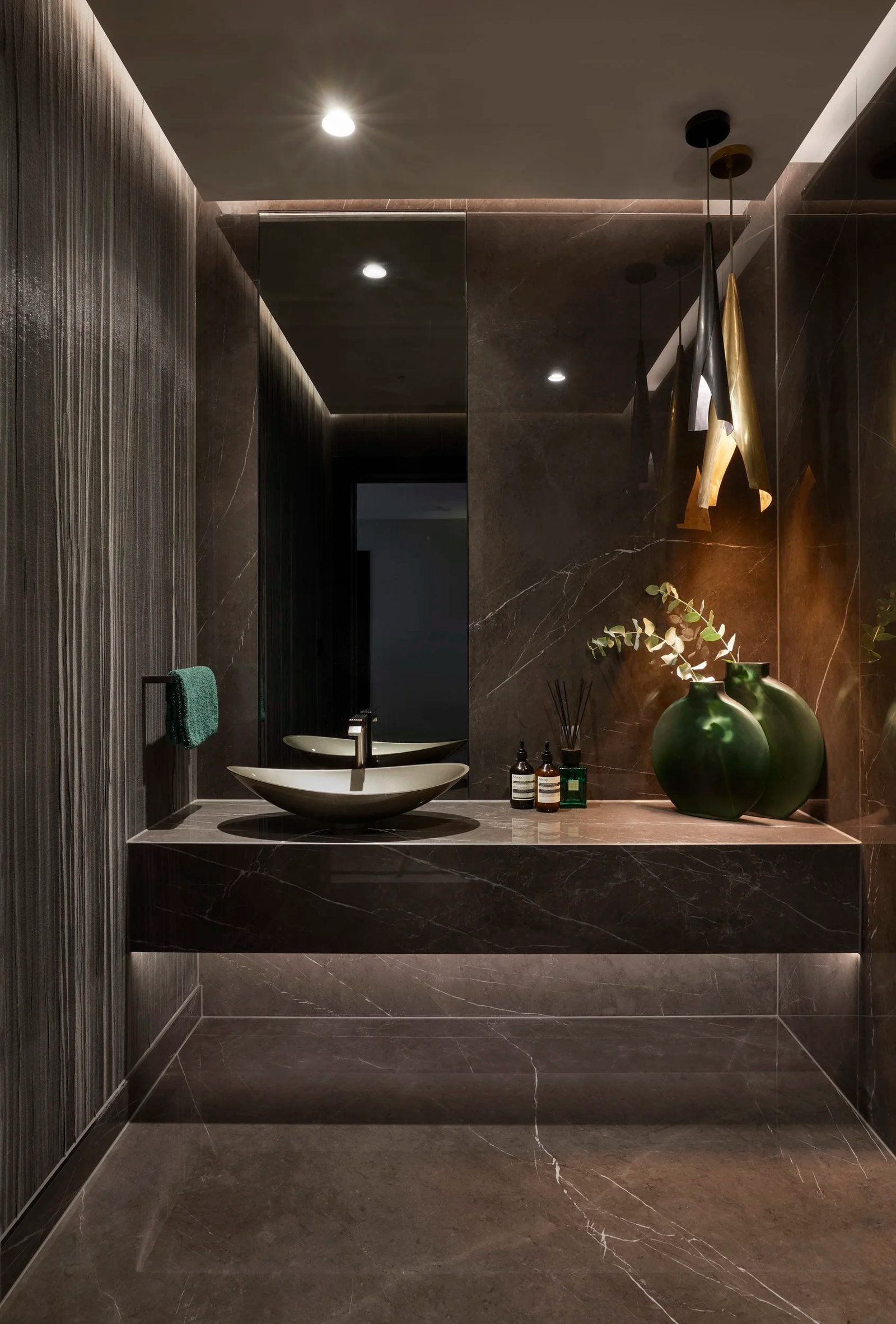 Marble bathroom vanity with a stone basin and green glass vases