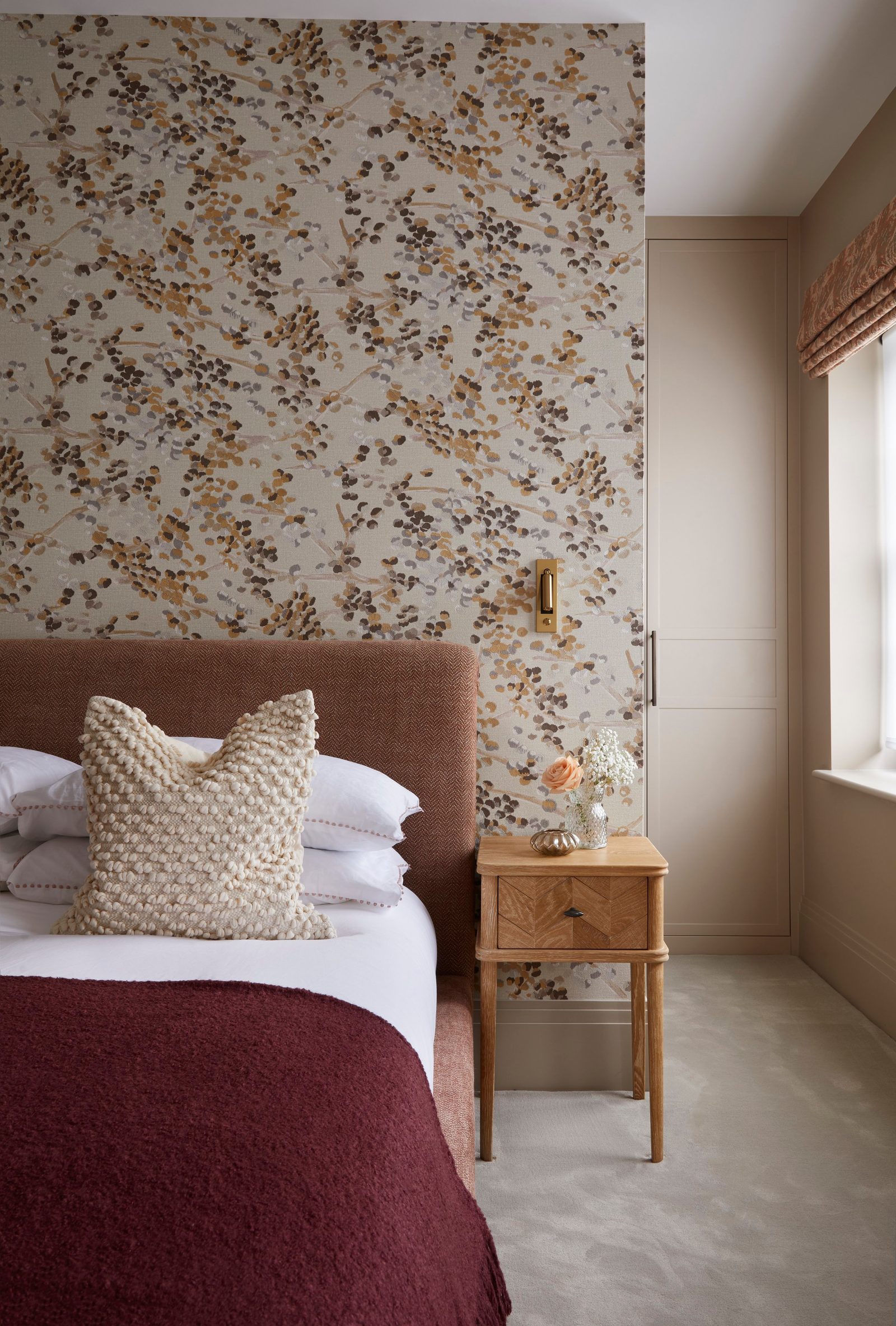 Bedroom with floral wallpaper, rust headboard and oak bedside table