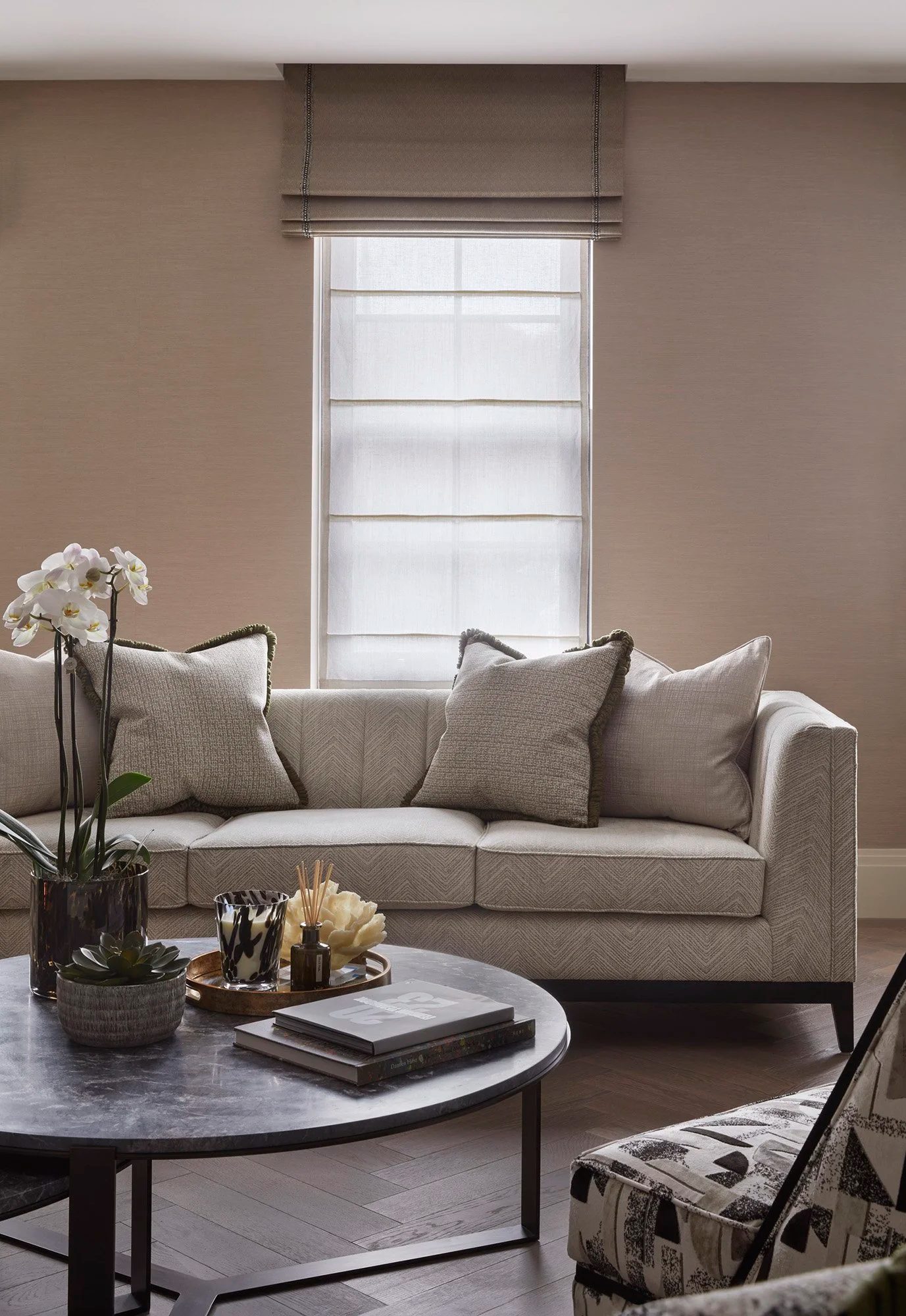 Linen sofa beneath a window with orchids and a marble coffee table